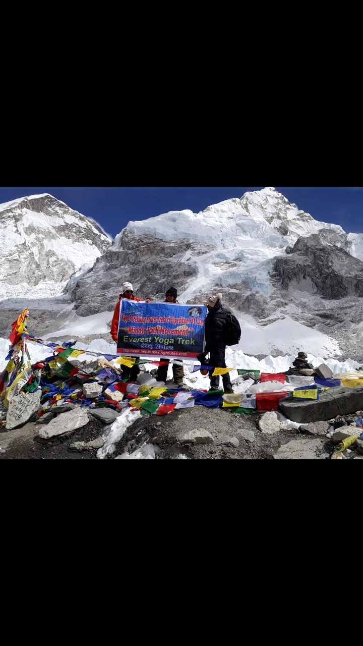 Des gens tenant une bannière dans un lieu montagneux enneigé avec des drapeaux de prière.