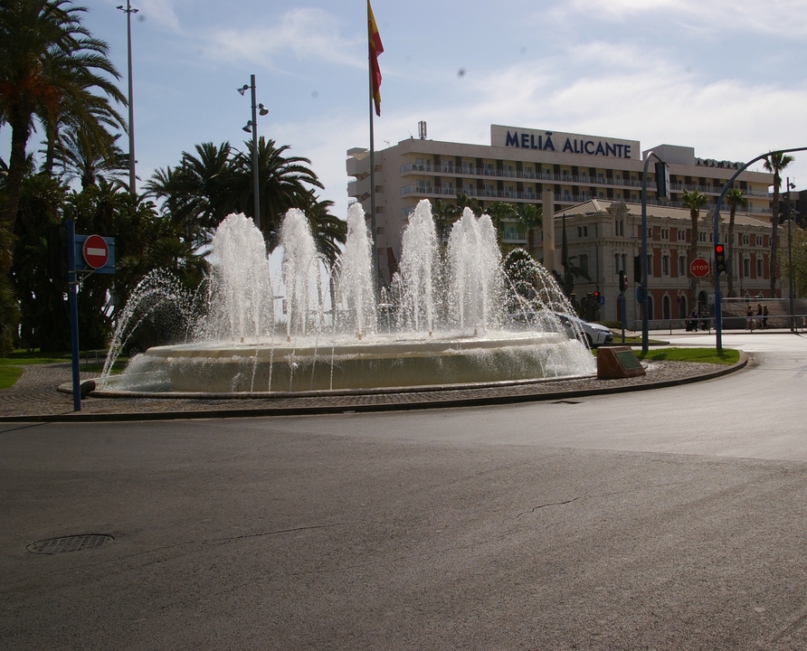 Fontaine dans un rond-point avec un bâtiment d'hôtel à proximité.