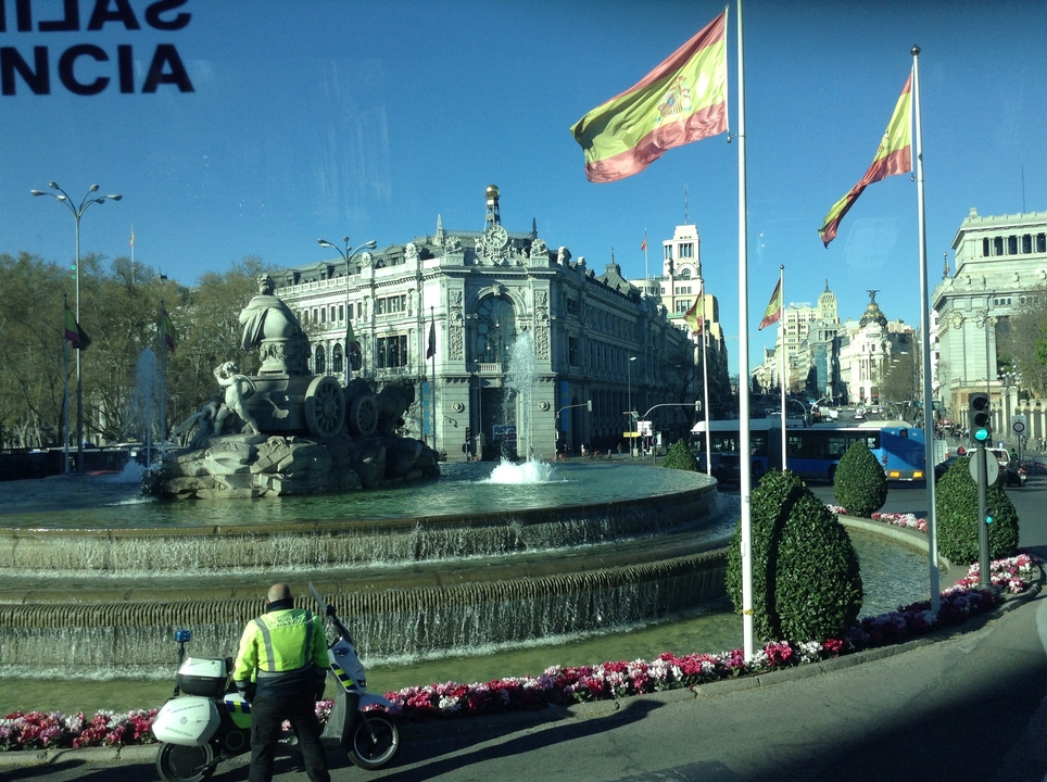 Fontaine devant un bâtiment historique avec des drapeaux.