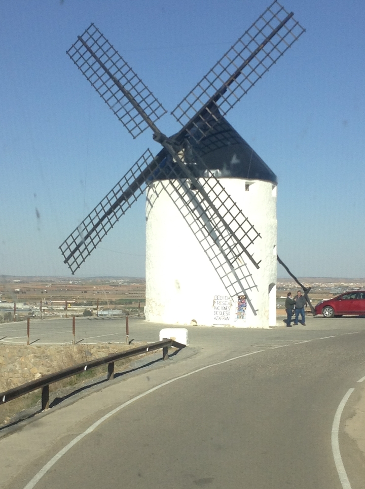 Moulin à vent traditionnel avec des personnes à proximité, surplombant une vallée.