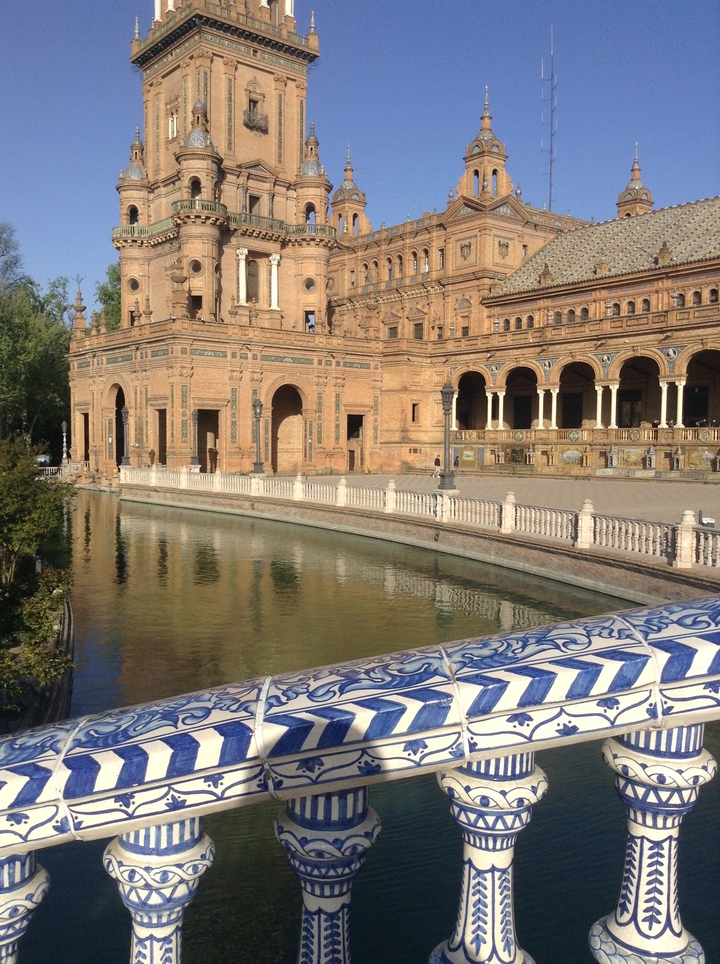 Place historique avec un canal reflétant un bâtiment orné.