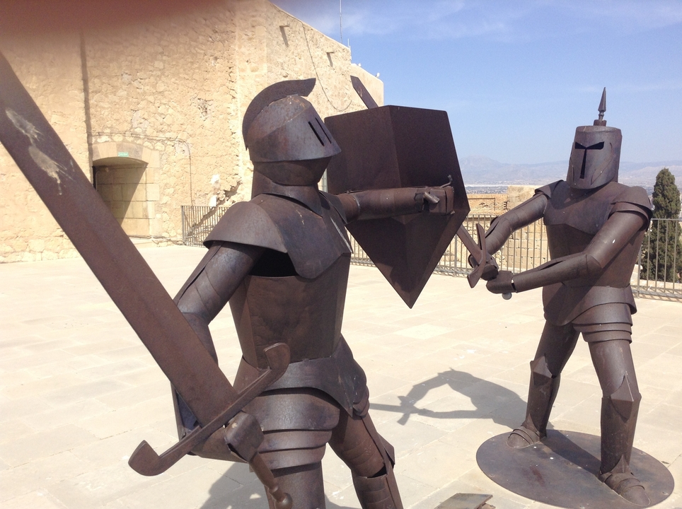 Sculptures de chevaliers en métal dans un décor de château.