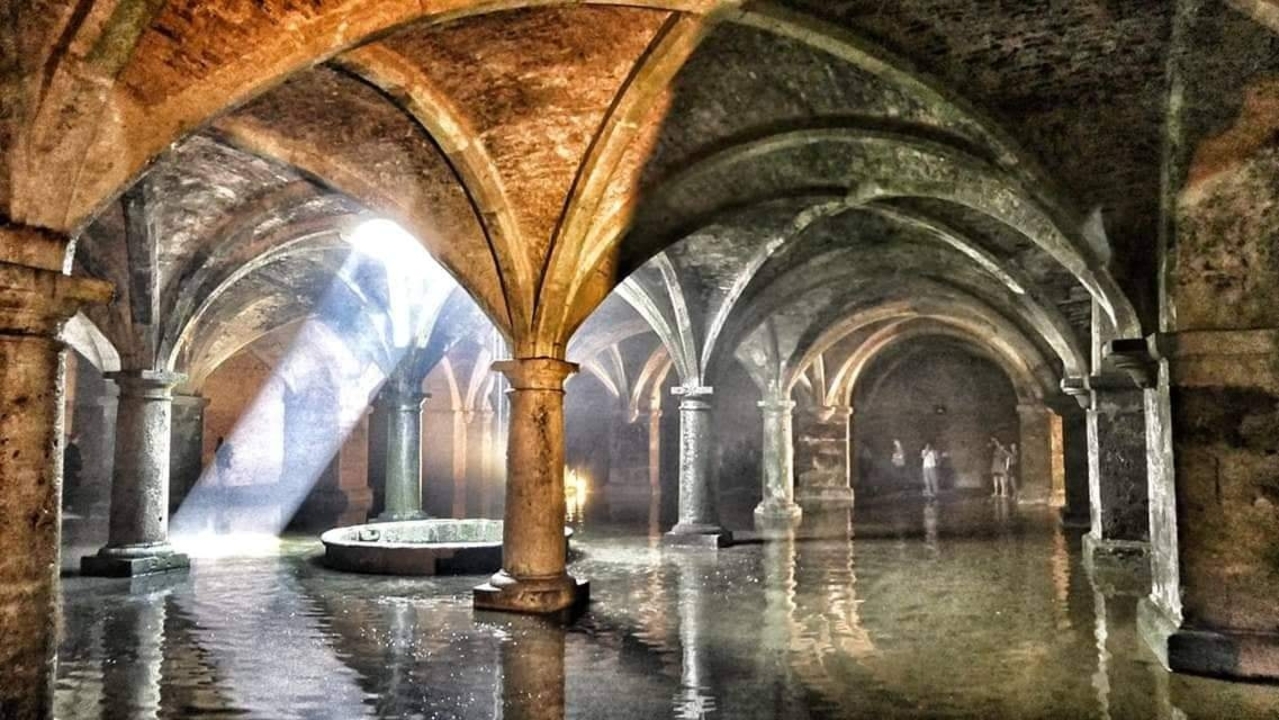 Une pièce d'eau souterraine avec des plafonds voûtés et de la lumière qui filtre à l'intérieur.