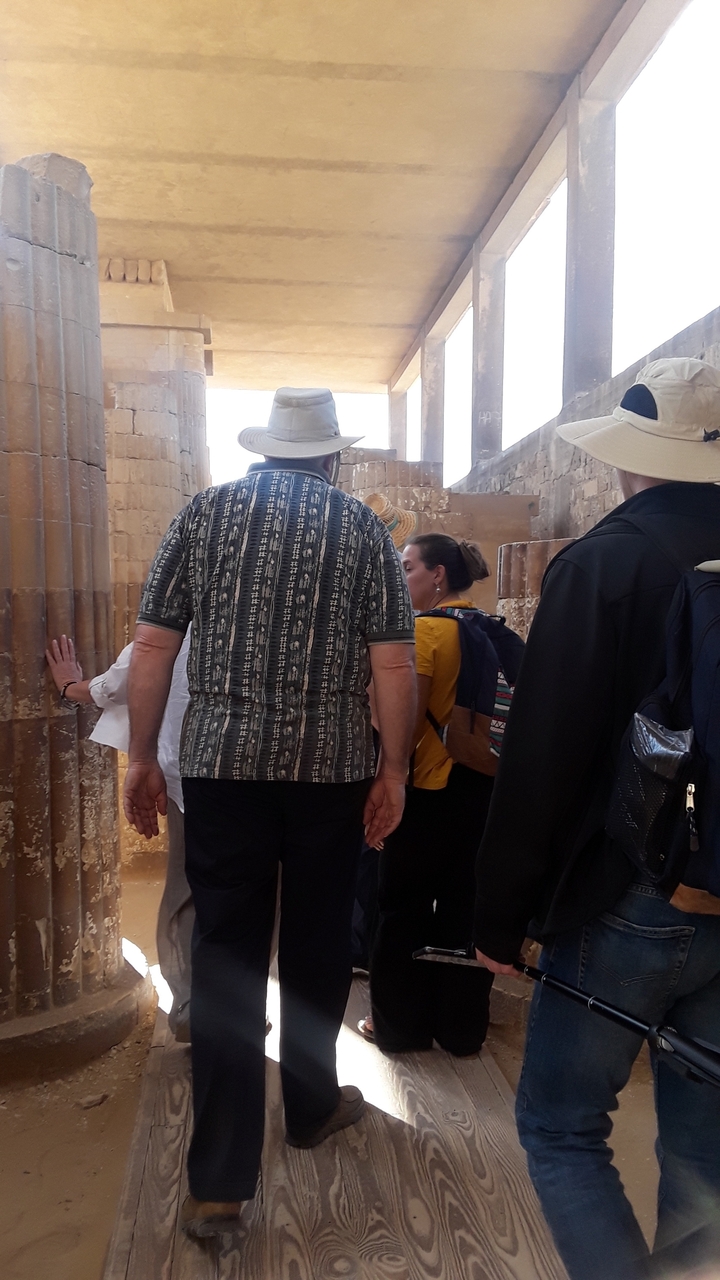 Des gens marchant à travers d'anciennes colonnes ornées de hiéroglyphes.
