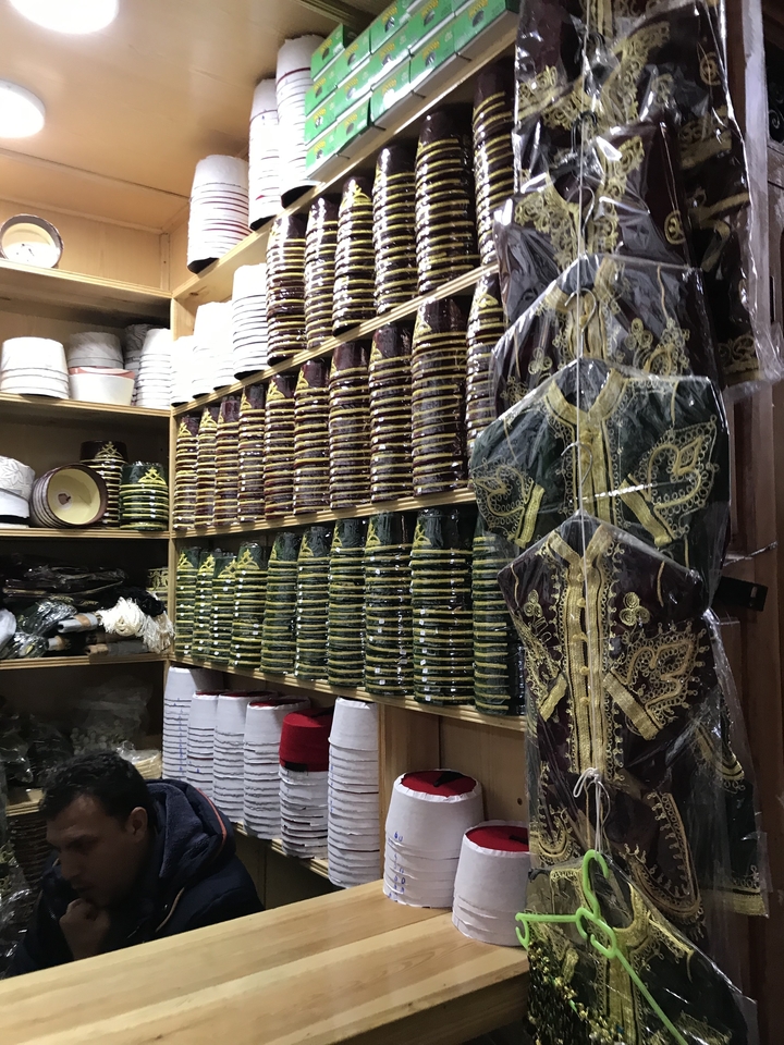 Rangées de chapeaux traditionnels et de vêtements dans une boutique.