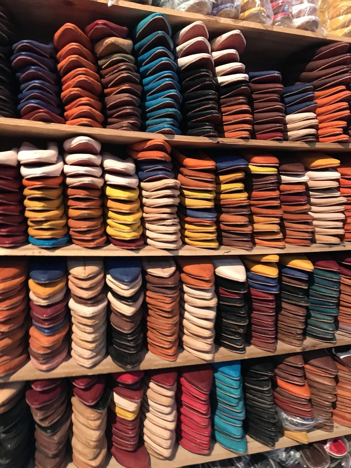 Une collection de babouches marocaines traditionnelles empilées dans une boutique.
