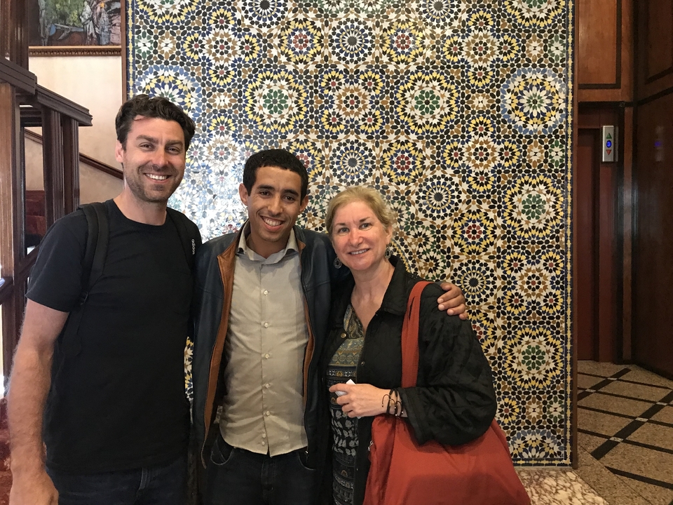 Un groupe pose devant un arrière-plan de carrelage marocain traditionnel.