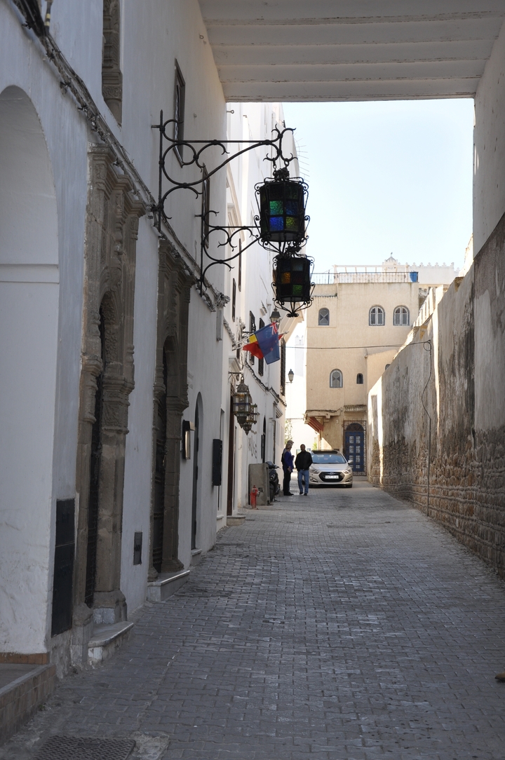 Rue étroite dans une médina avec des gens et des drapeaux