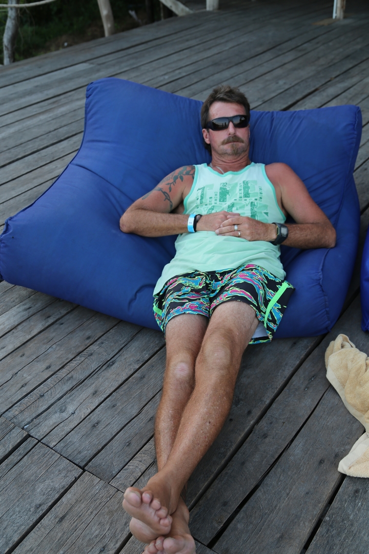 Homme se prélassant sur un pouf poire sur une terrasse en bois.