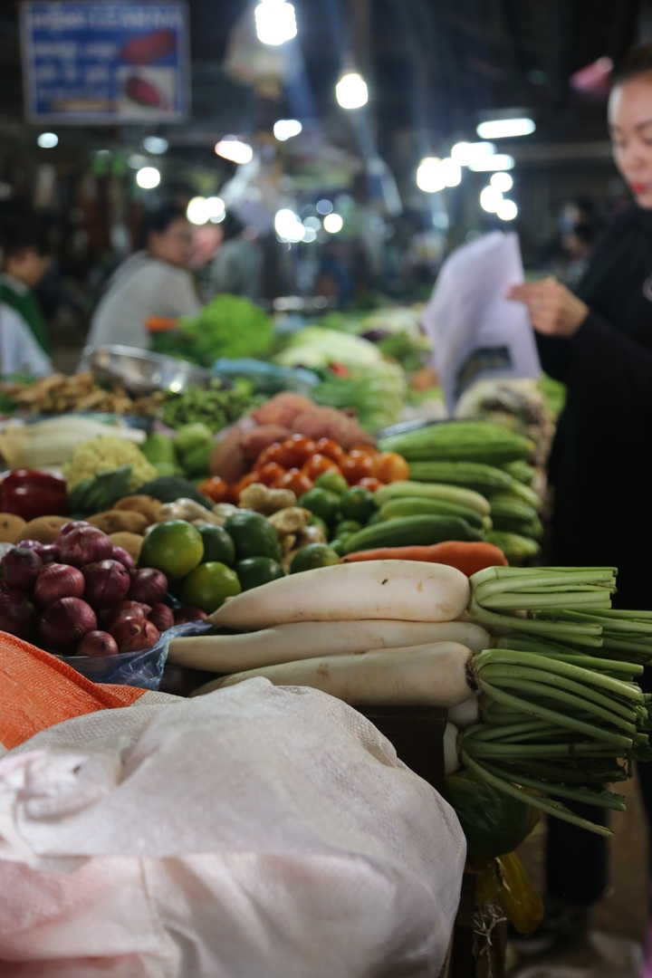 Gros plan de divers légumes exposés sur un étal de marché.