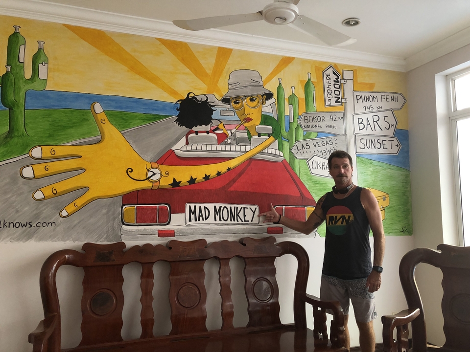 Homme pointant du doigt une peinture murale de dessin animé avec une voiture et un panneau de signalisation.