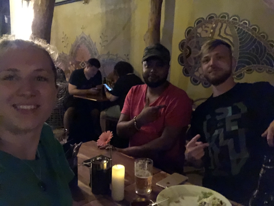 Trois personnes assises à une table faiblement éclairée dans un bar.