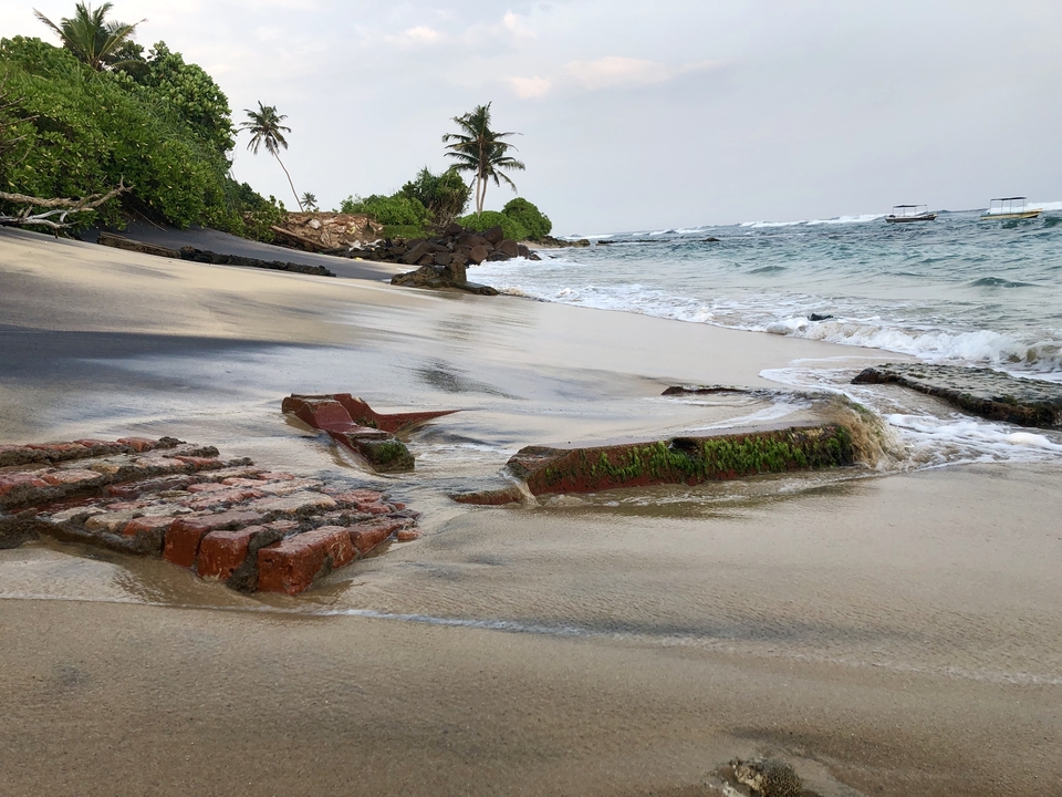 Plage avec marée montante et briques éparses.