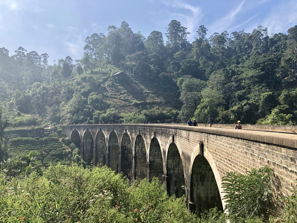 Pont à neuf arches au-dessus d'une végétation luxuriante et de collines.