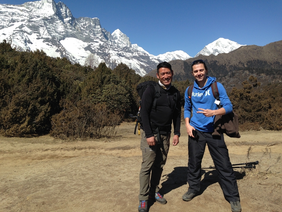 Deux hommes posant devant un paysage montagneux.