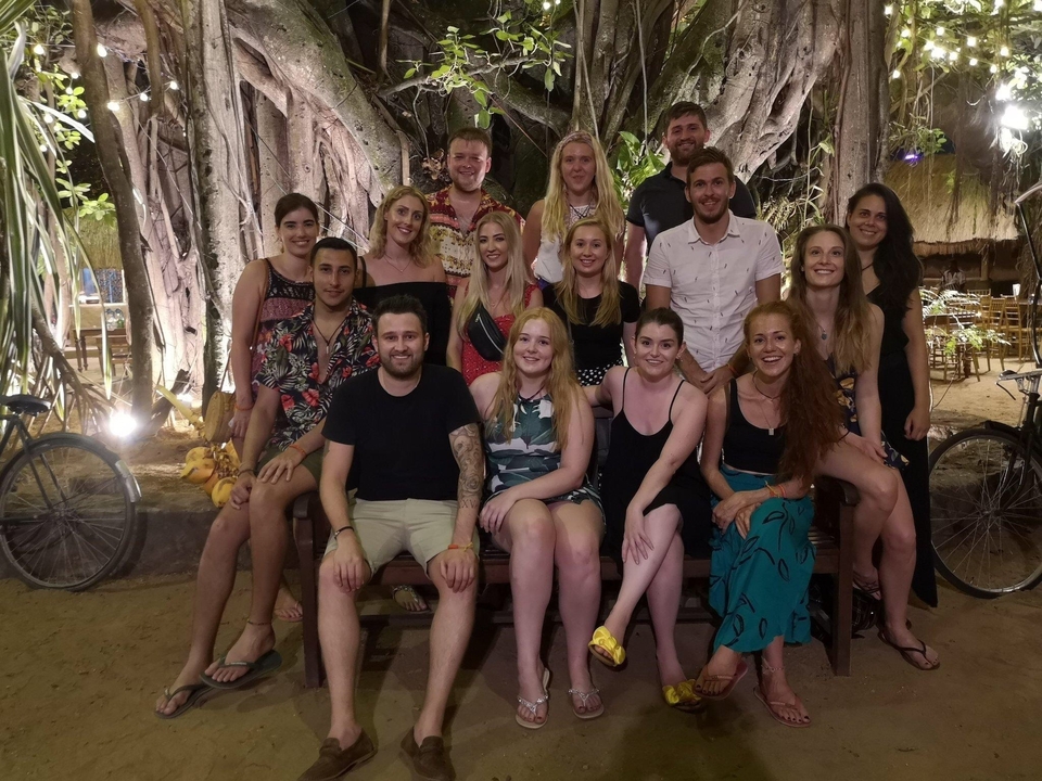 Groupe de personnes rassemblées devant un grand arbre la nuit