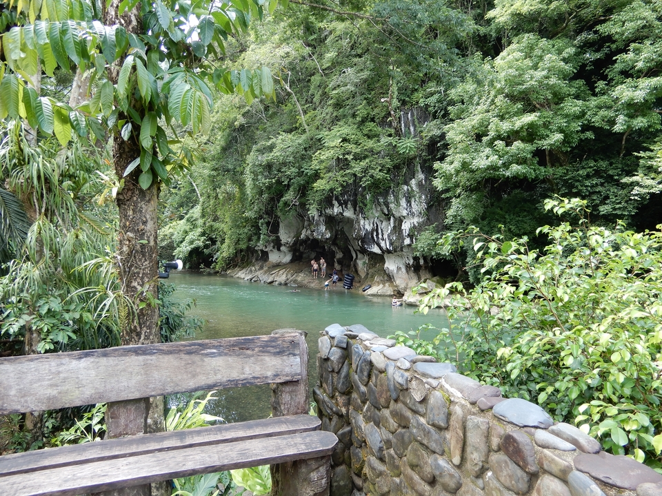 Lac entouré d'une végétation luxuriante et de falaises rocheuses avec des gens qui profitent de l'eau.