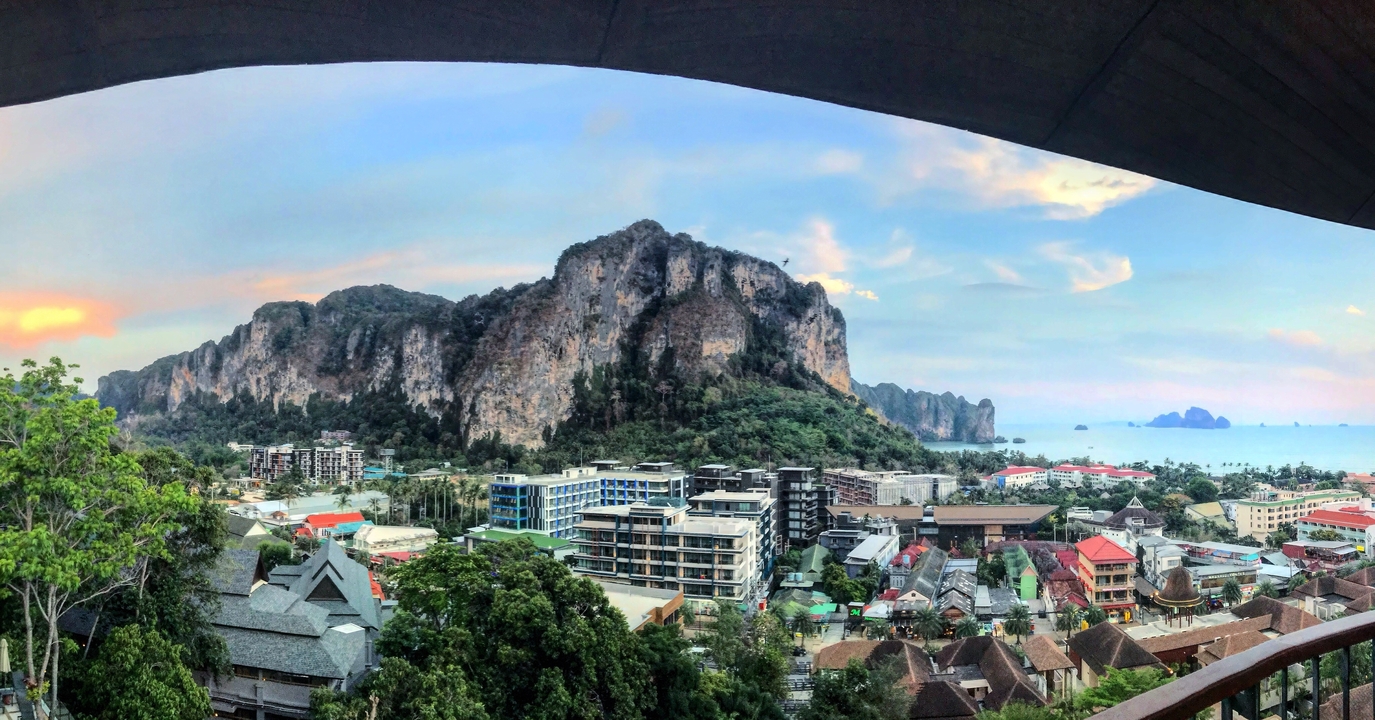 Vue panoramique d'une ville côtière avec un arrière-plan montagneux.