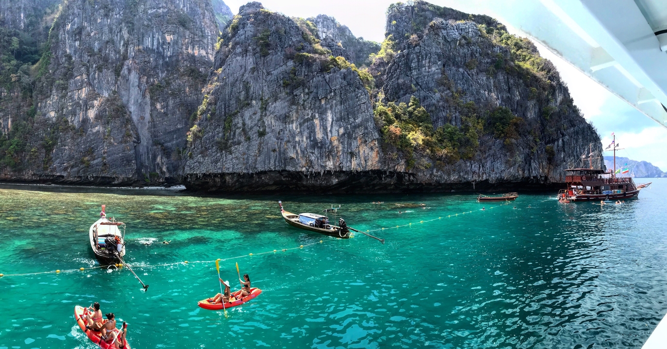 Bateaux flottant près de grandes falaises calcaires ; des gens faisant du kayak dans la région.