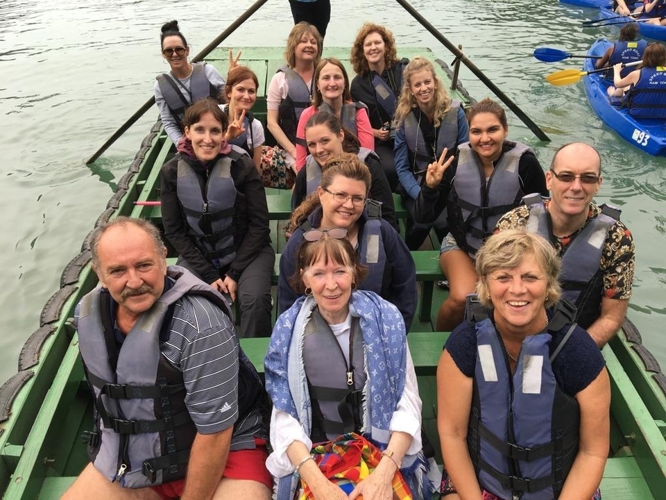 Groupe de personnes dans un bateau portant des gilets de sauvetage, sur l'eau.