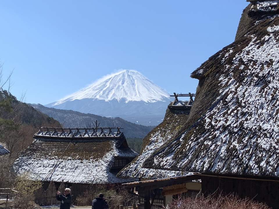 Snow-covered Mount Fuji with traditional roofs in the foreground