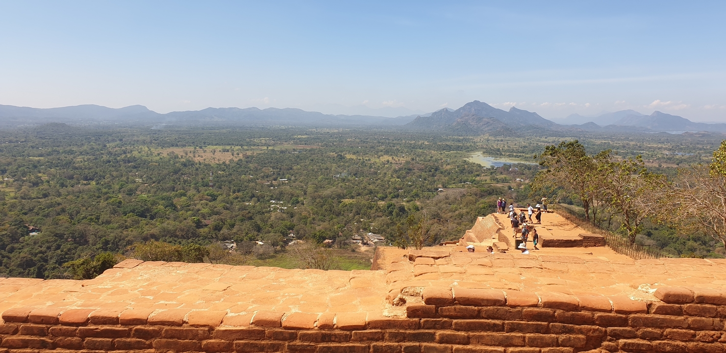 Des touristes explorant un site antique avec des vues panoramiques d'en haut.