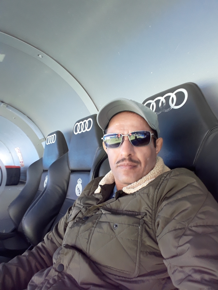 Personne assise sur un banc de stade avec des logos de marques visibles.