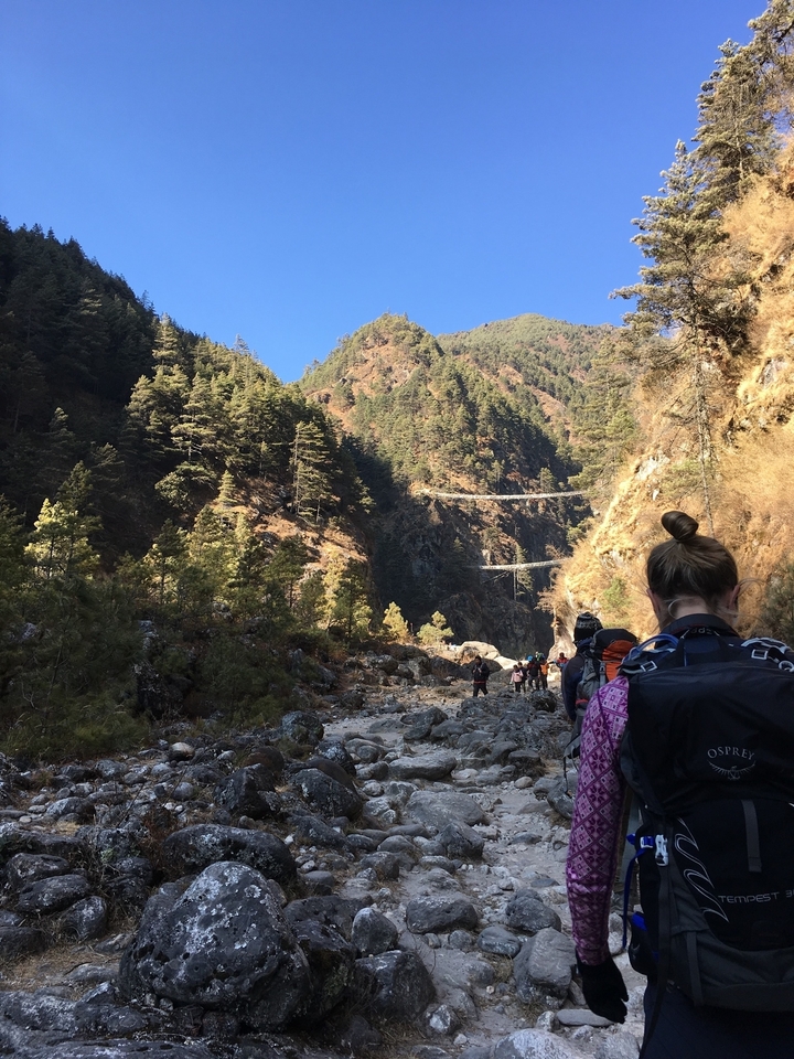 Un groupe de randonneurs sur un sentier rocheux avec des ponts suspendus.