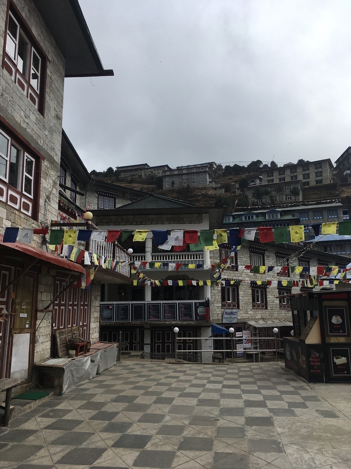 Rue avec bâtiments traditionnels et drapeaux de prière.