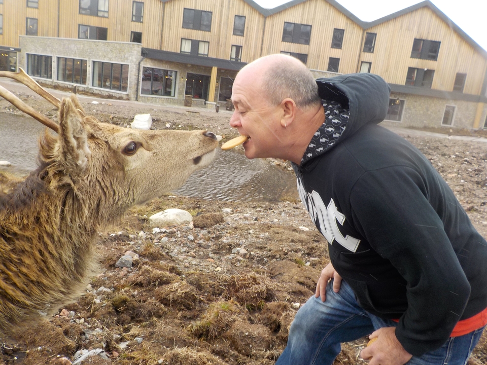Homme nourrissant un cerf avec la bouche dans un cadre extérieur.