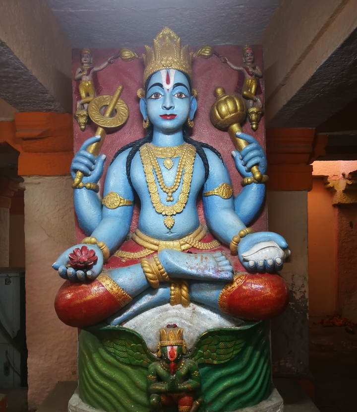 Statue colorée d'une divinité aux détails complexes.