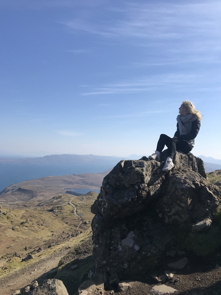 Person sitting on a rock, overlooking a vast landscape.
