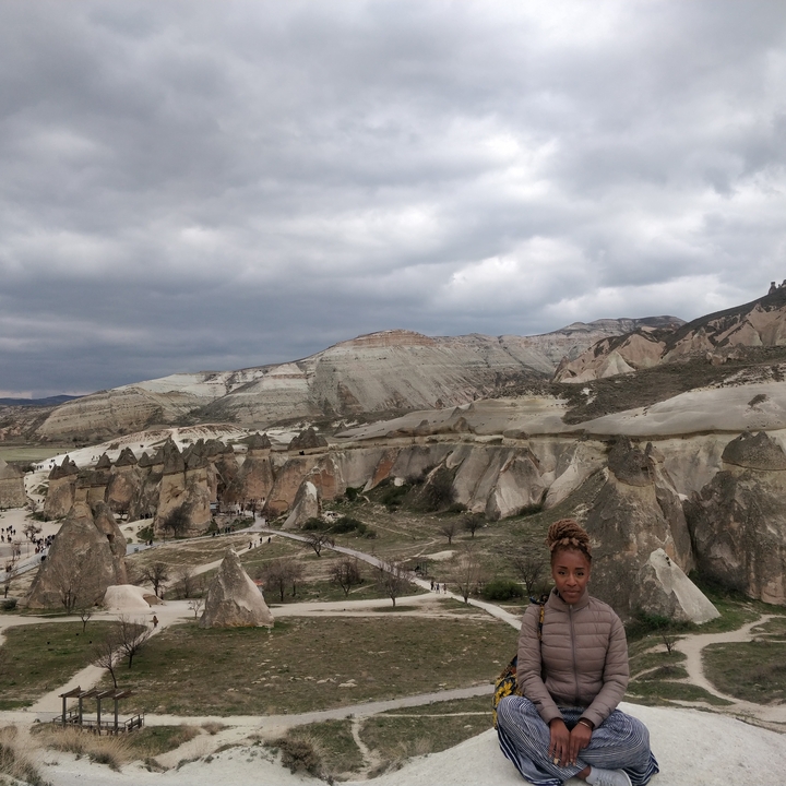 Personne posant avec des formations rocheuses en arrière-plan.