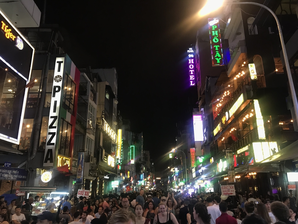Scène de rue animée avec des enseignes au néon et des hôtels la nuit.