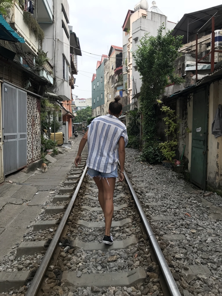 Personne marchant sur des voies ferrées à côté de maisons résidentielles.