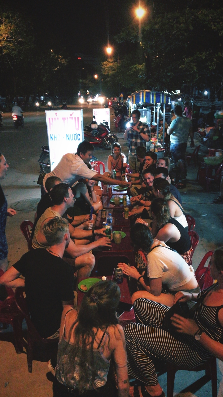 Groupe de personnes dînant en plein air dans la lumière du soir.