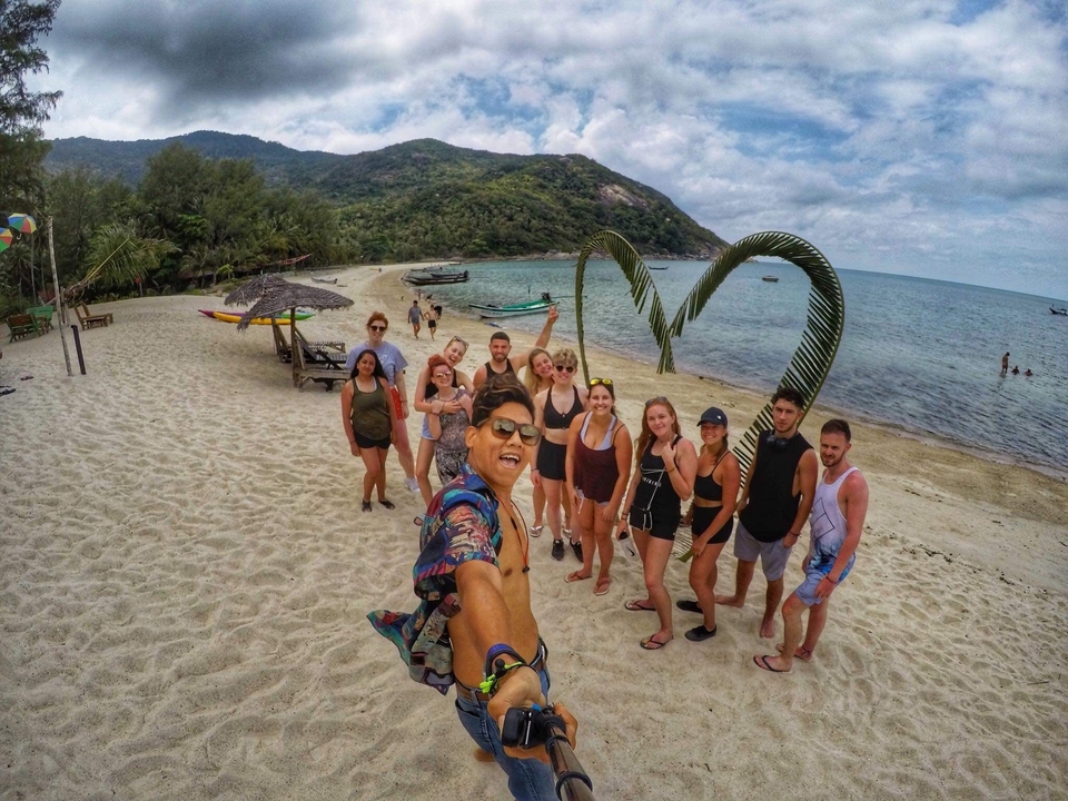 Group of people on a sandy beach posing for a photo with the sea in the background.