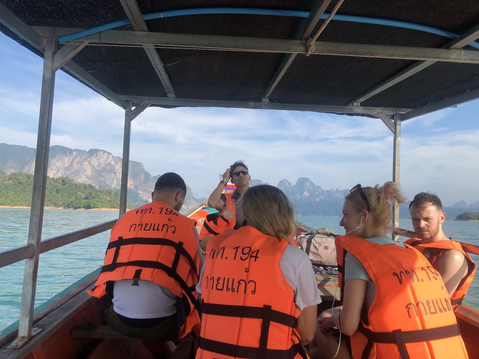 People on a boat wearing life jackets with distant mountains.