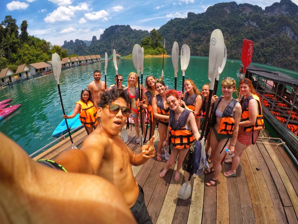 Group with kayak paddles on a dock by floating accommodations.