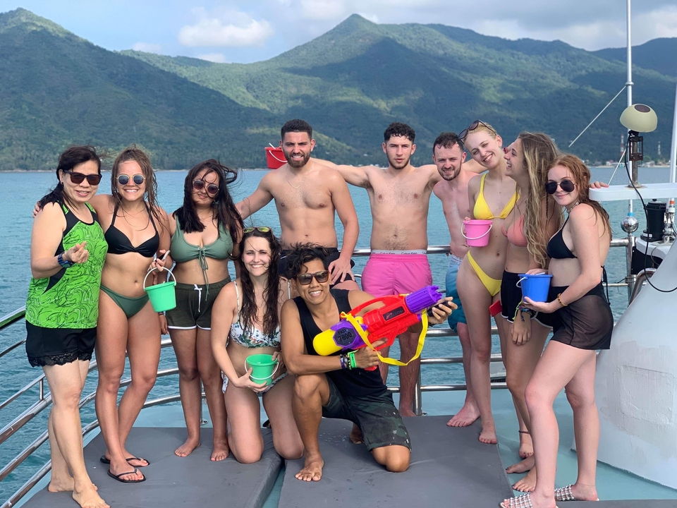 Group on a boat with water pistols enjoying the sun.