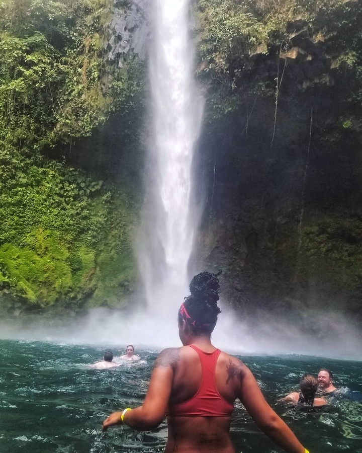 Une personne debout devant une cascade.