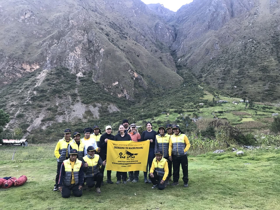Un groupe de randonneurs posant avec une bannière dans une région montagneuse.