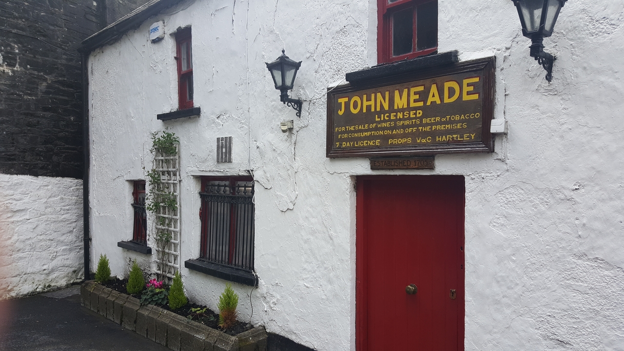 Un pub irlandais traditionnel avec des murs blancs et des accents rouges.