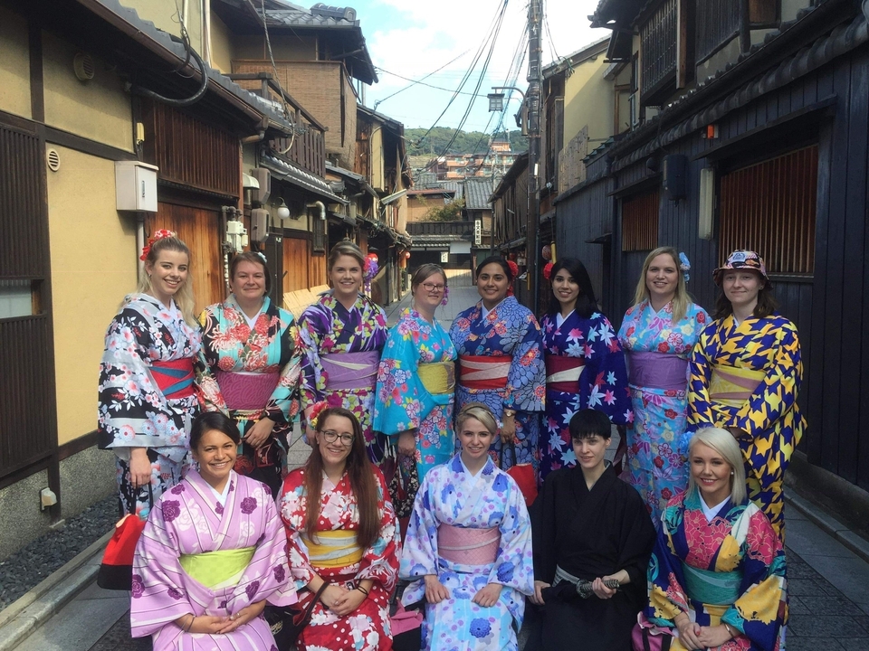 Groupe de personnes portant des kimonos colorés dans une rue traditionnelle.