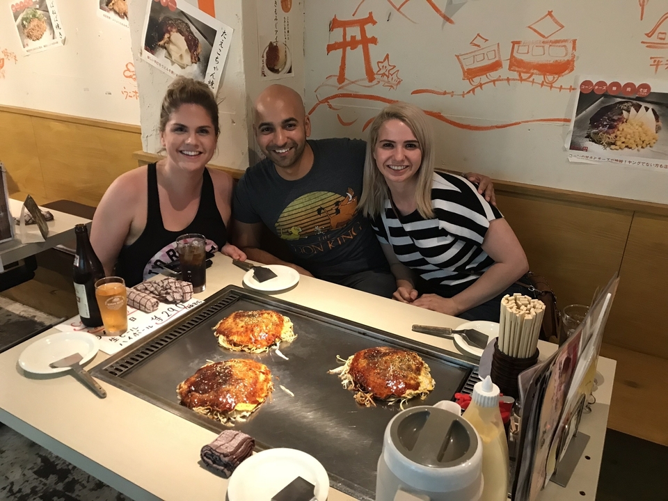 Trois personnes assises à une table avec de l'okonomiyaki.