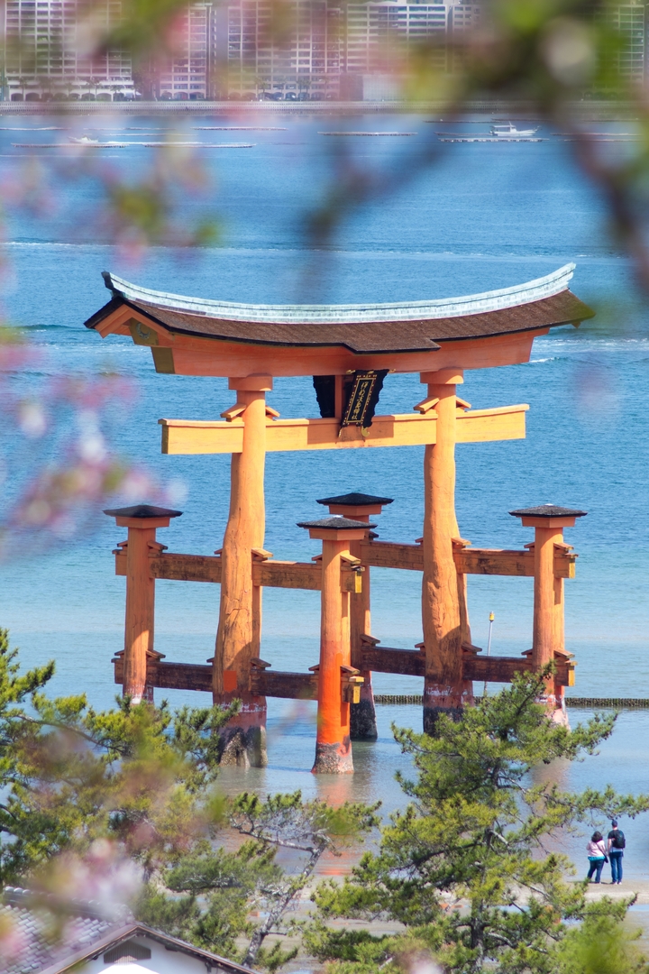 Grand torii partiellement immergé dans l'eau avec vue lointaine sur l'océan.