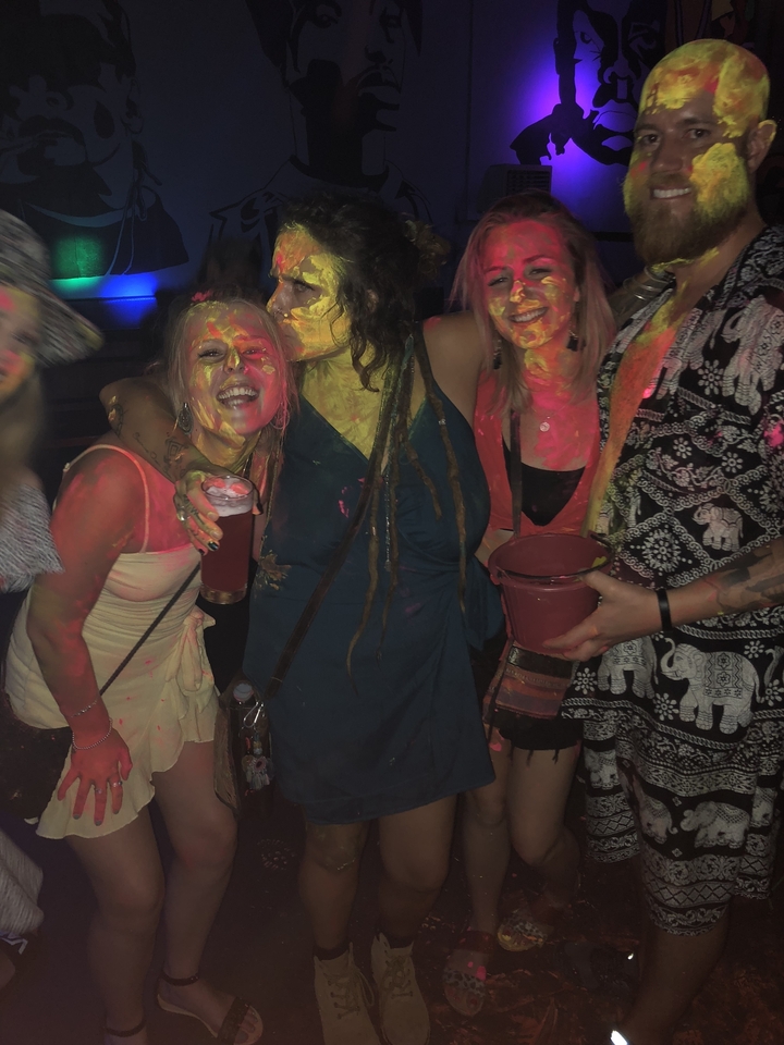 Groupe de personnes avec de la peinture sur le visage, tenant des boissons lors d'une fête.