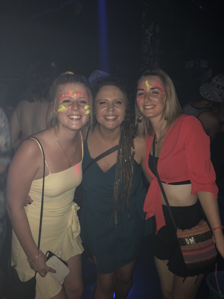 Trois personnes souriantes aux visages peints lors d'un événement nocturne.