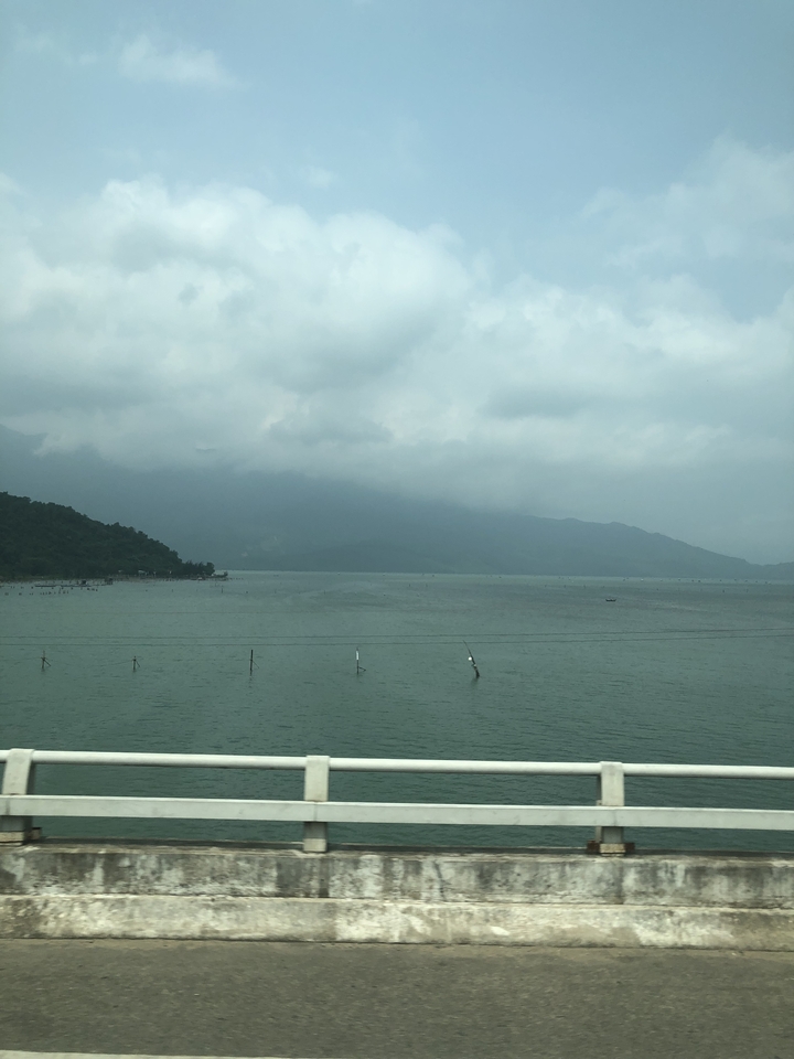 Vue brumeuse d'une grande étendue d'eau entourée de collines.