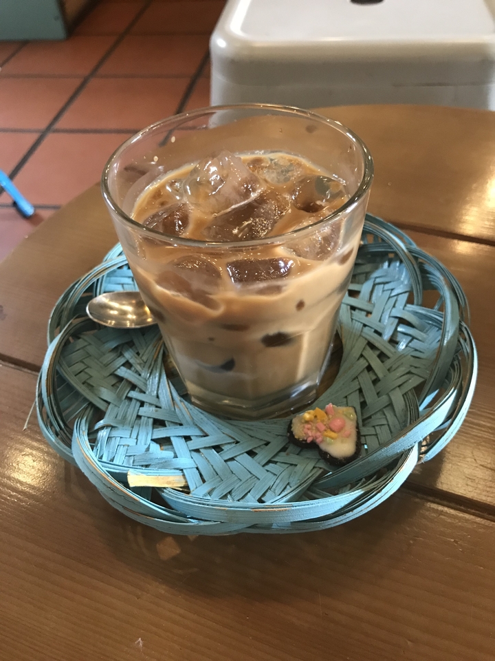 Verre de café glacé avec garniture florale sur une table.